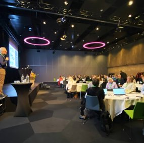 Bilde av salen fra Storfellesmøtet 2023 . På scenen står en av innlederne.