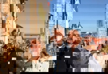 En kvinne og to menn står foran et murhus med utsikt over Tallinn by i bakgrunnen.