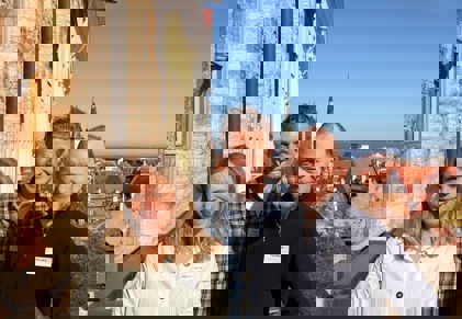 Three people standing in front of a stone wall overlooking the city of Tallinn.