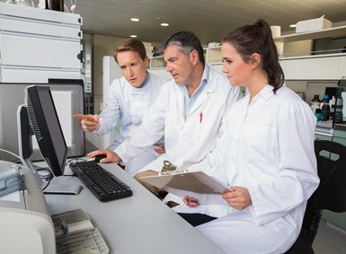 Tre forskere ser på en dataskjerm sammen