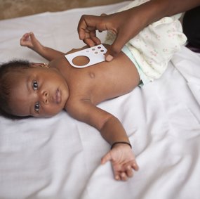 Baby med fargeskala-verktøy i papp på brystet