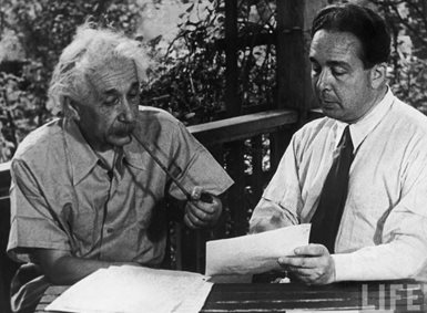 Albert Einsten og Leo Szilard sitter på en veranda og ser på et ark sammen. 