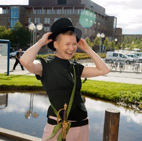 Elina Halttunen står utendørs og holder en flosshatt på hodet. Hun har ordensbånd og sabel på seg.